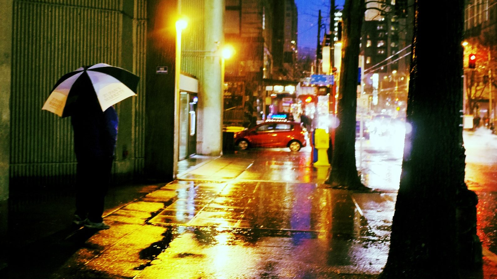 Person walking on a Seattle, Washington, street holding an umbrella on a rainy day.
