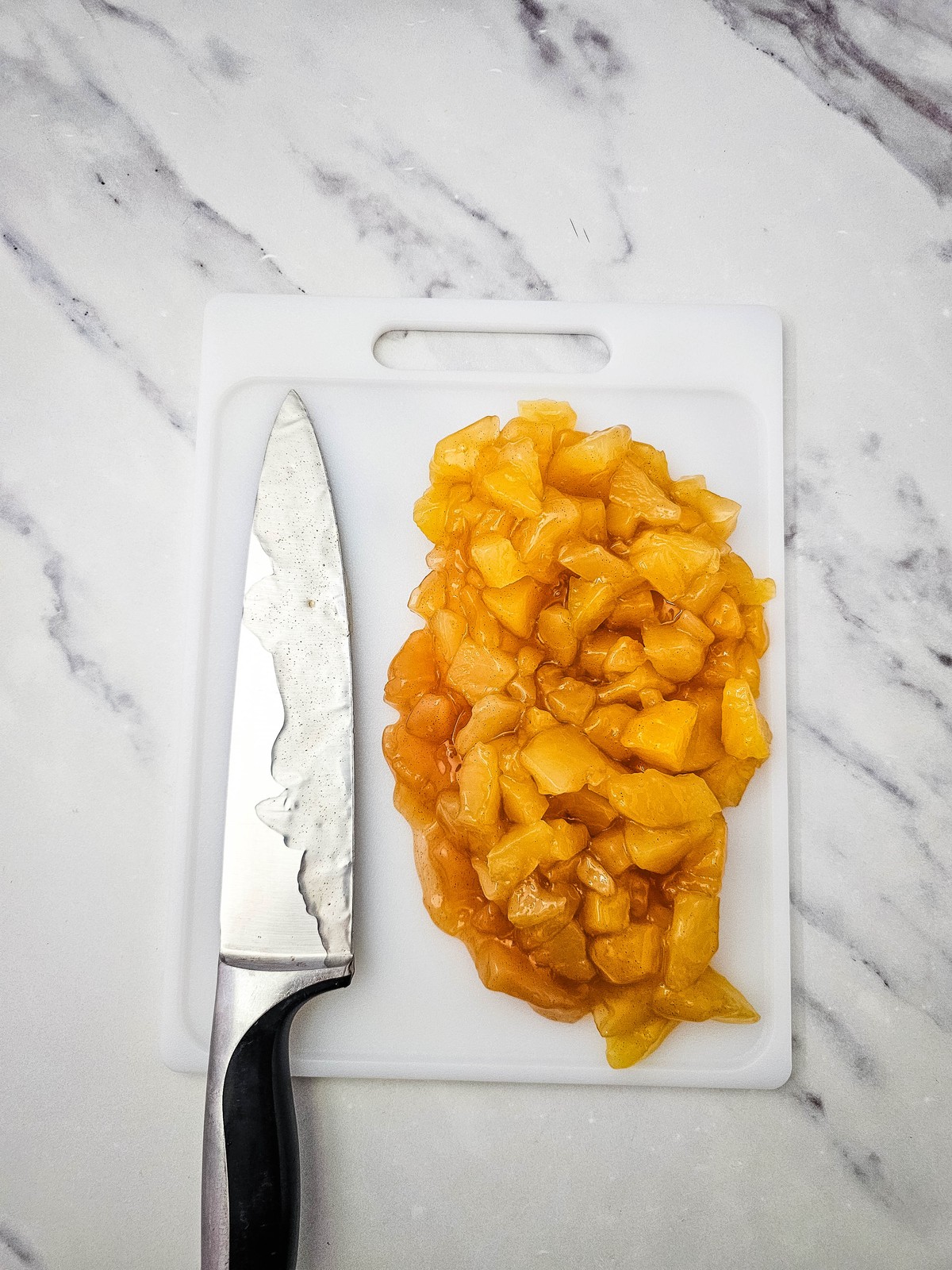 Apple pie filling chopped into small pieces on a cutting board with a knife