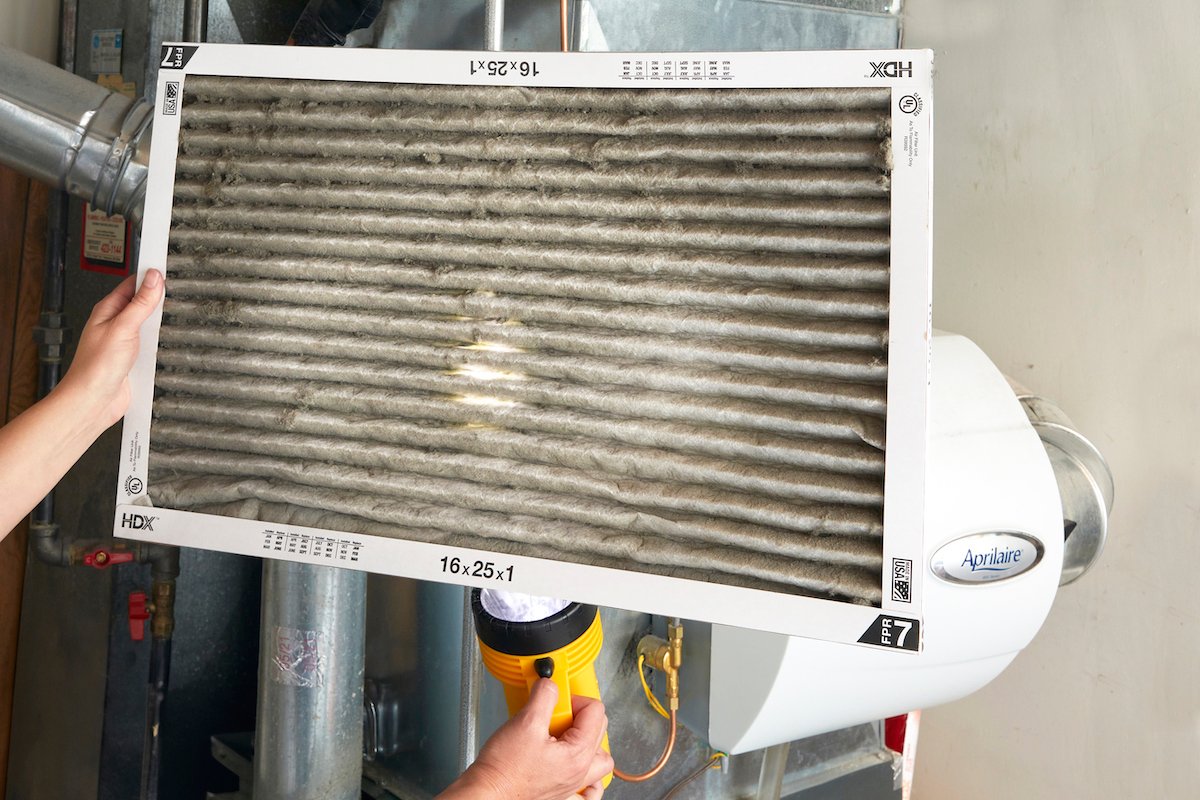 Woman holds up a dirty pleated furnace filter.