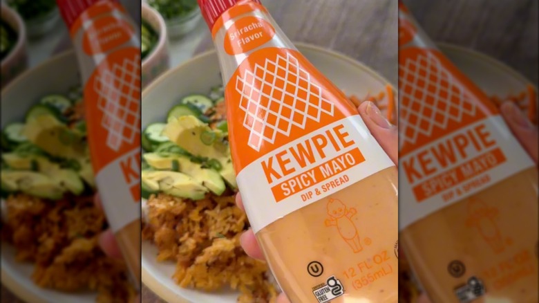 Somebody holding a bottle of the Kewpie Spicy Mayo over a bowl of food