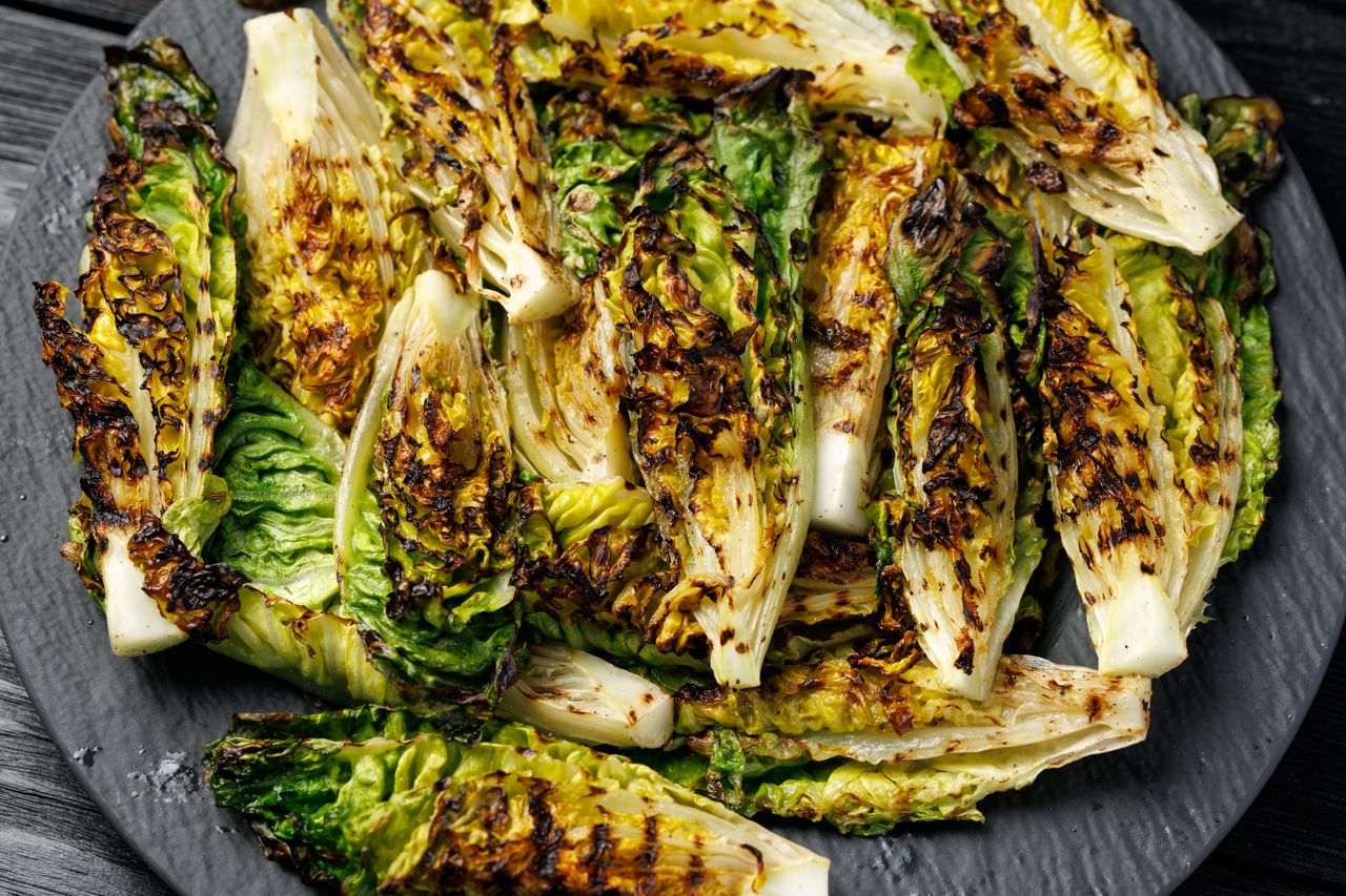 Grilled romaine lettuce pieces on a dark plate