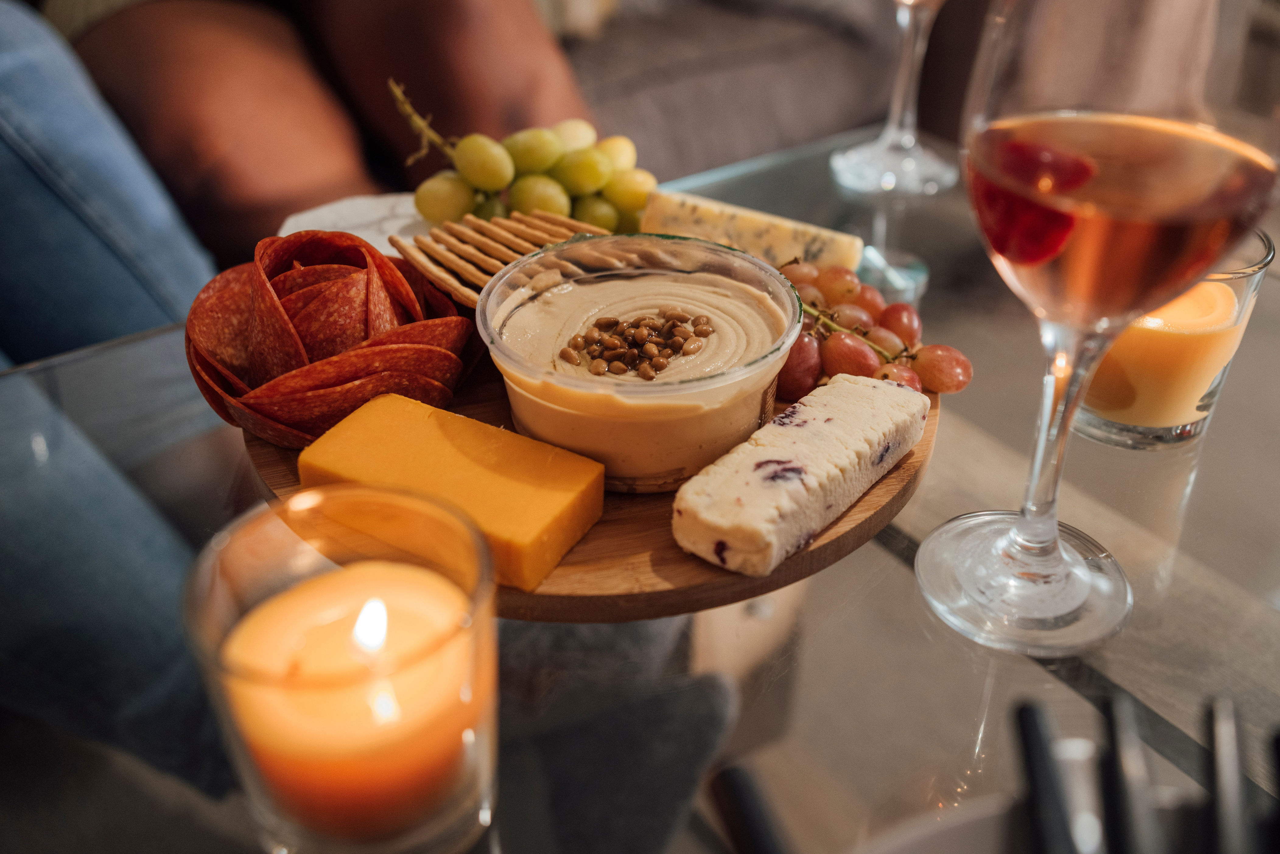 A charctuerie board surround by wine glasses and lit candles