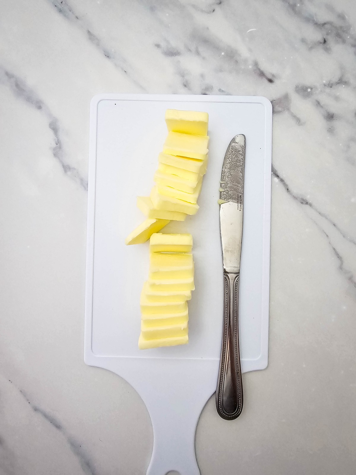Stick of butter cut into thin slices on a cutting board