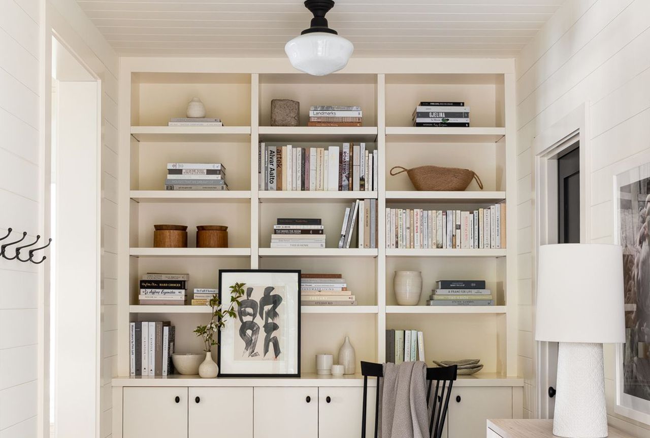Builtin shelving unit containing books and decorative items with a cabinet underneath and a chair positioned nearby