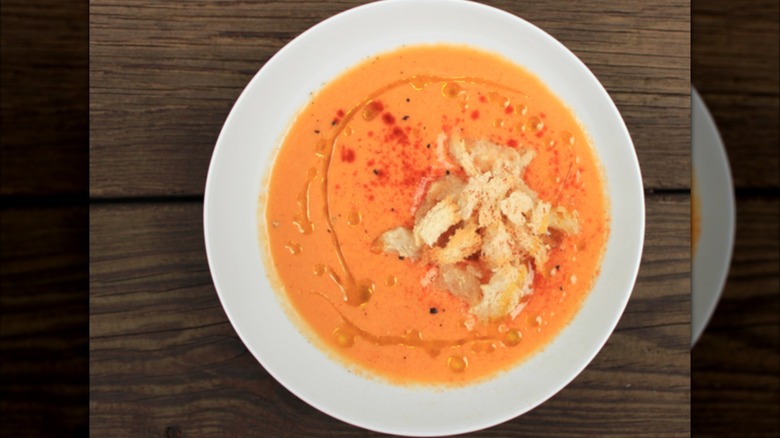 White bowl of gazpacho on wooden table