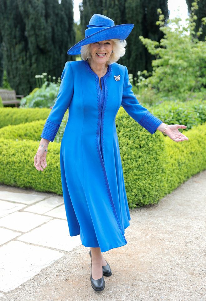 Queen Camilla in a blue jacket and hat smiling