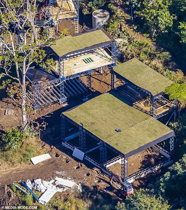 One image shows a cluster of raised pods built into the hillside and surrounded by dense native trees, while another reveals the home's green-roofed structures and open steel framework at close range