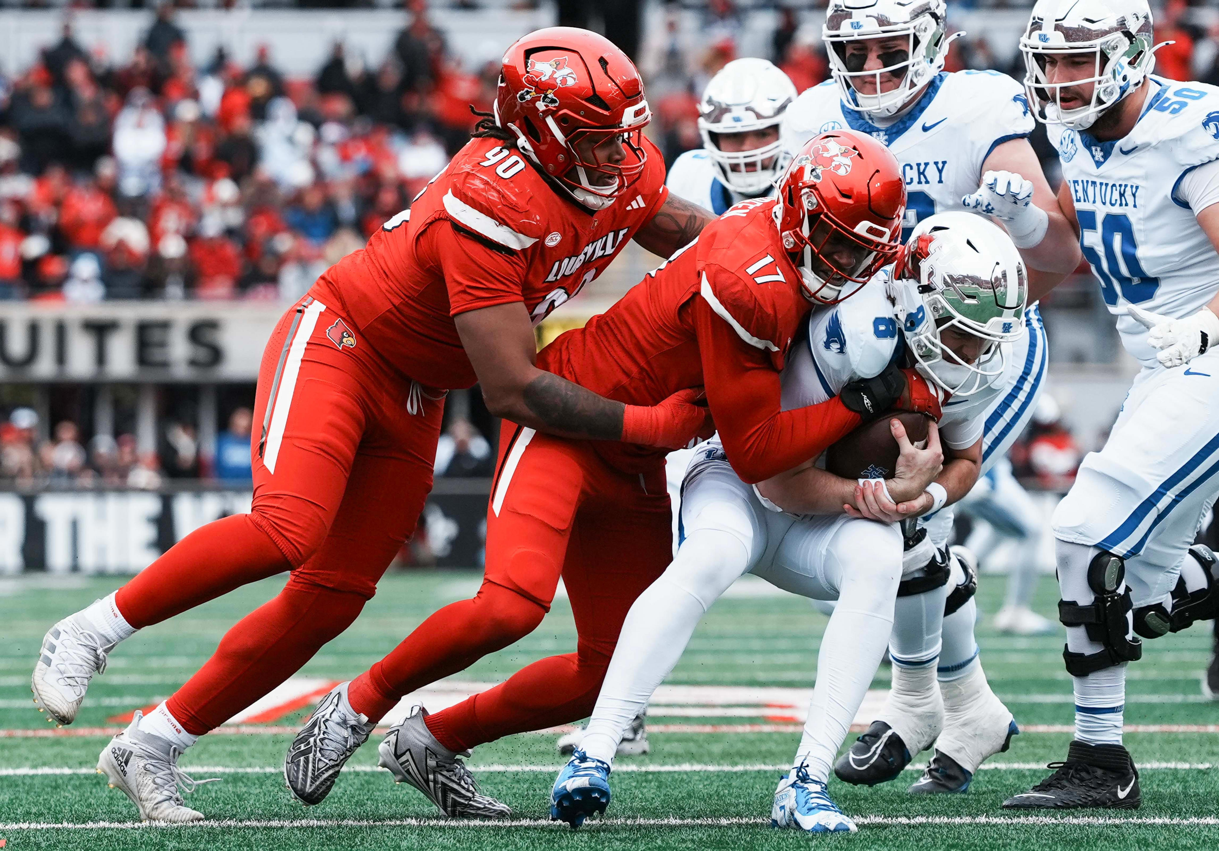 Louisville Cardinals defensive lineman AJ Green (17) grabs Kentucky Wildcats quarterback Cutter Boley (8) as Louisville Cardinals defensive lineman Clev Lubin (50) helps in the first half Saturday, November 29, 2025 in Louisville, Kentucky at L&N Federal Credit Union Stadium.