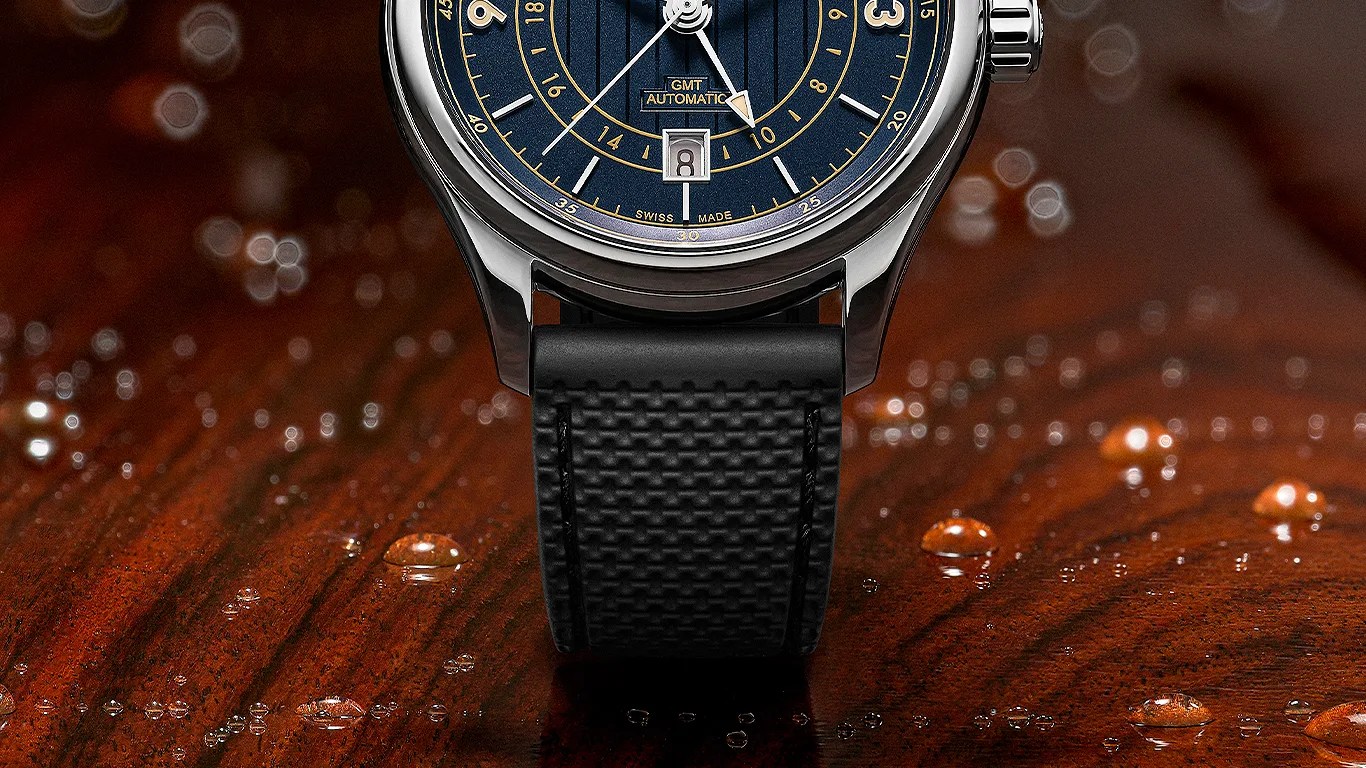 Close-up of a wristwatch with a blue dial, gold markings, date window, and black textured strap on a wet wooden surface.