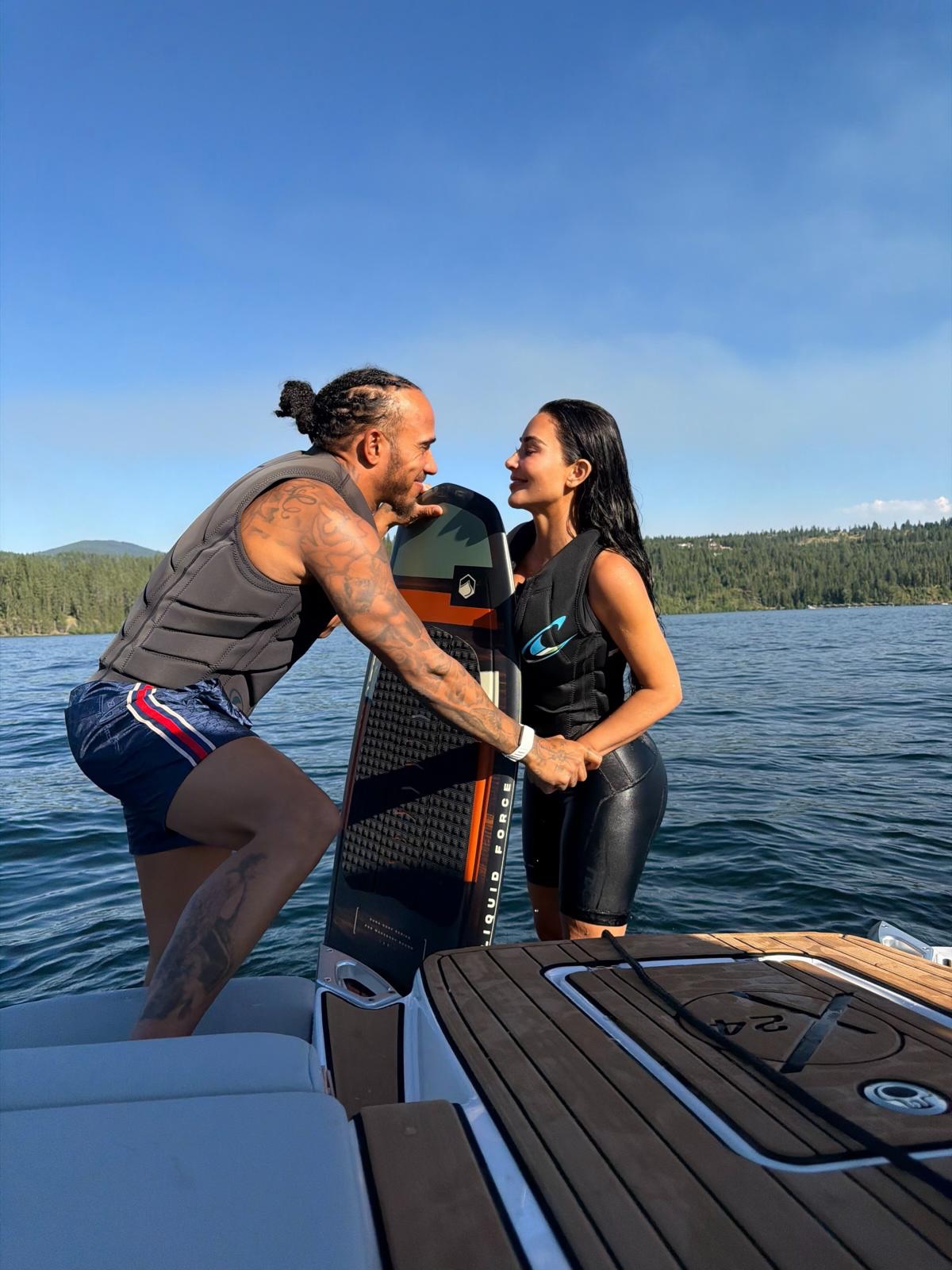 Lewis Hamilton and Kim Kardashian on a boat, holding a wakeboard.
