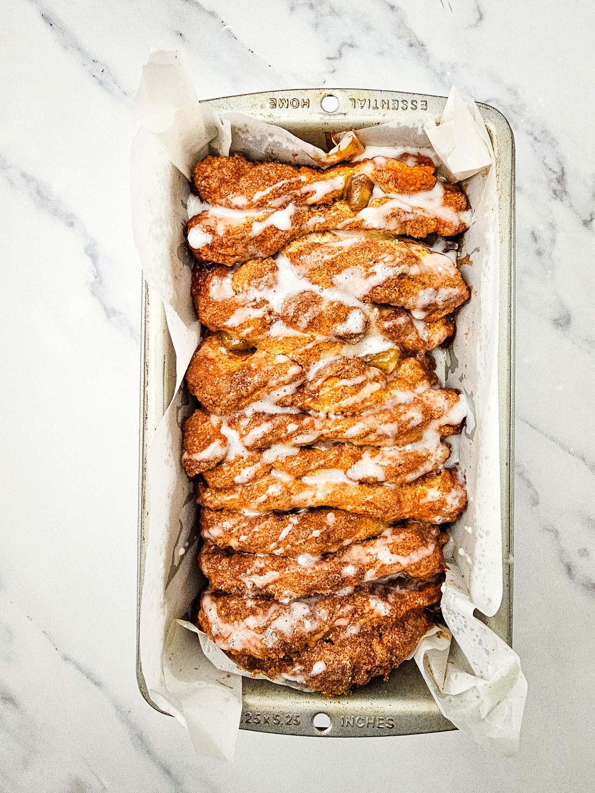 Powdered sugar glaze drizzled over the baked apple cinnamon biscuit loaf