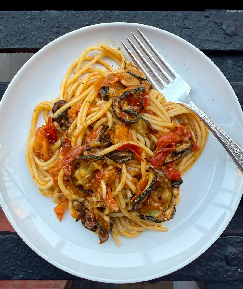 A plate of pasta with mixed vegetables and tomatobased sauce fork on the side