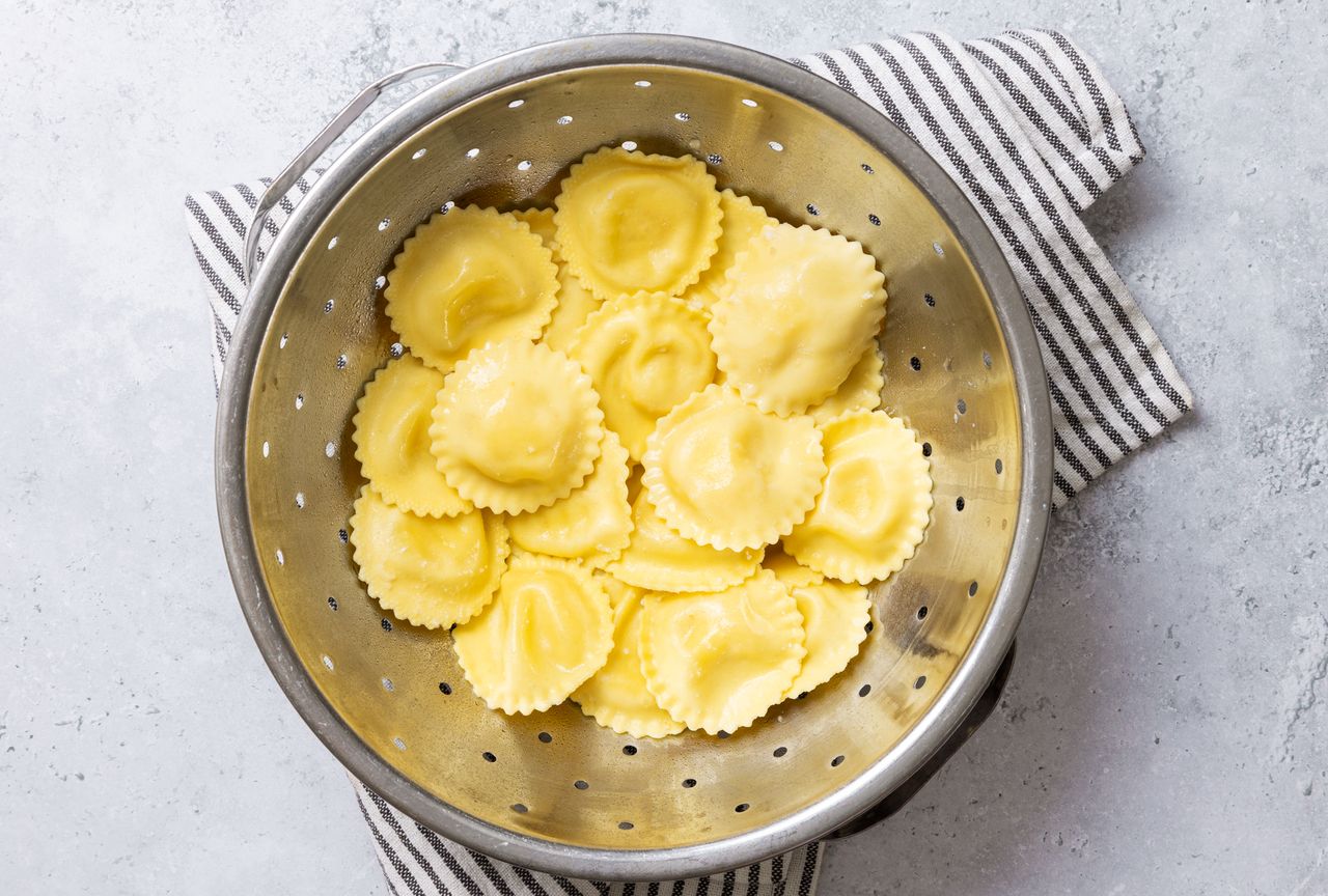 Ravioli draining in a colander on a striped towel
