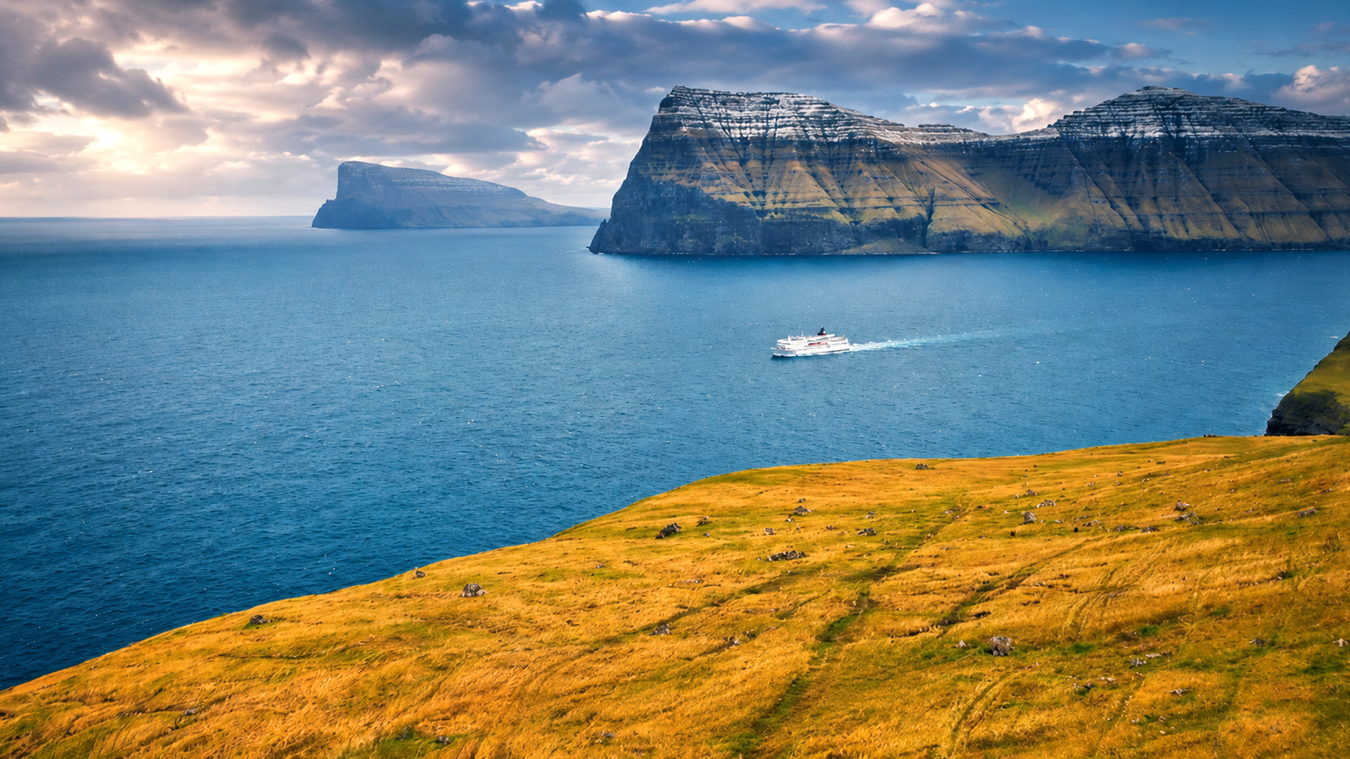 A ferry crossing beneath the Faroe Islands ocean cliffs