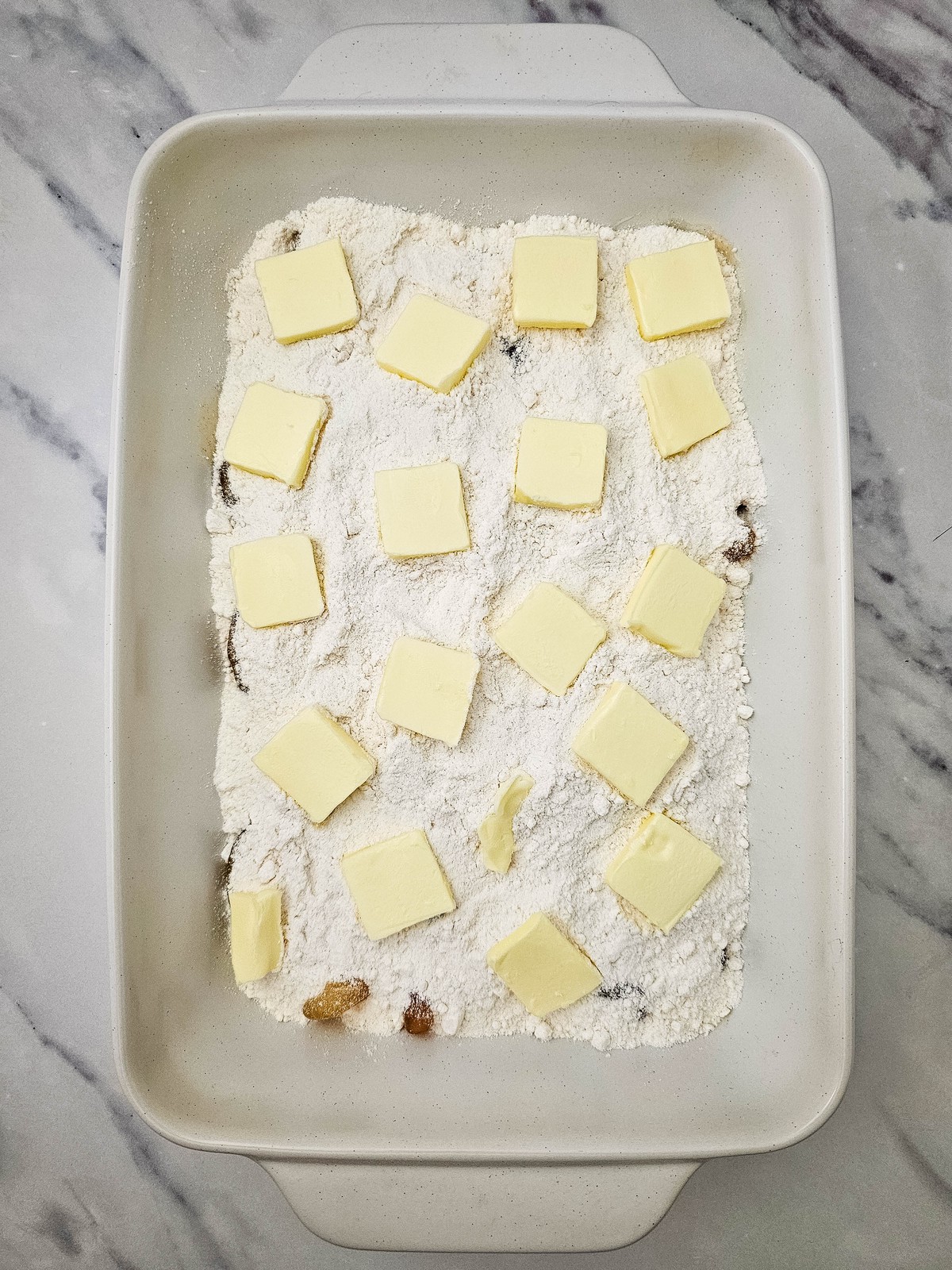 Thin butter slices arranged over the dry cake mix layer
