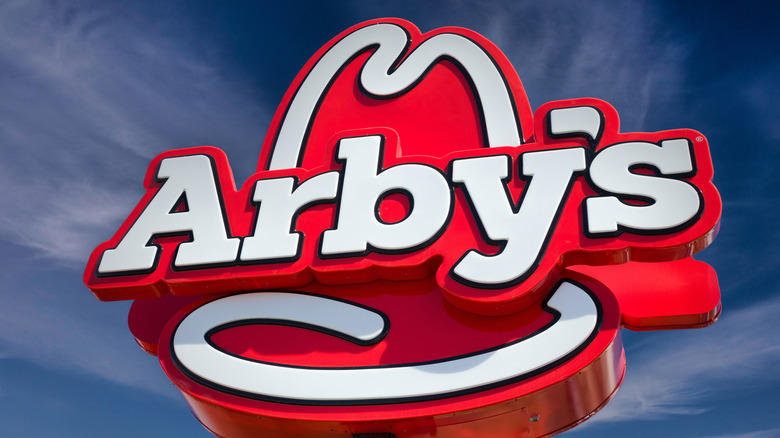 An Arby's restaurant sign stands against a blue sky