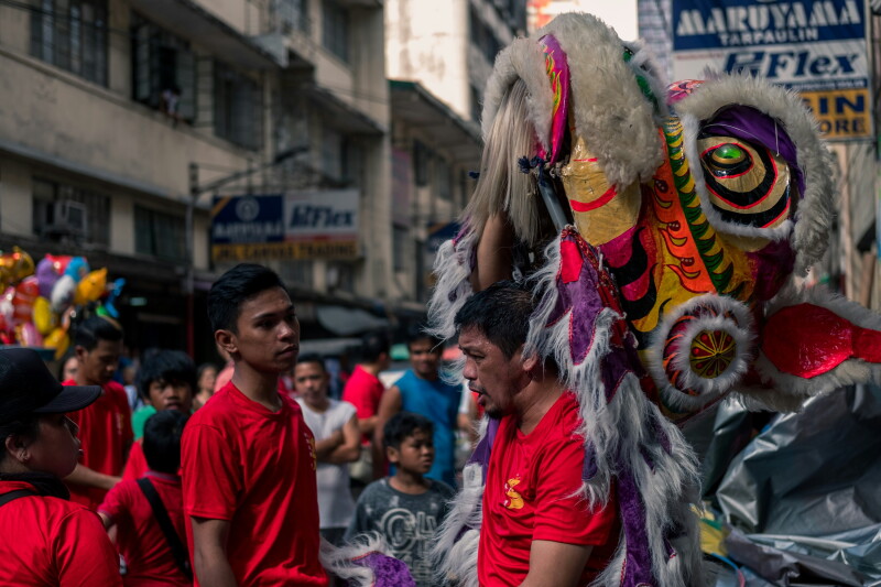A person holding up a dragon costumes in Manila's Binondo area