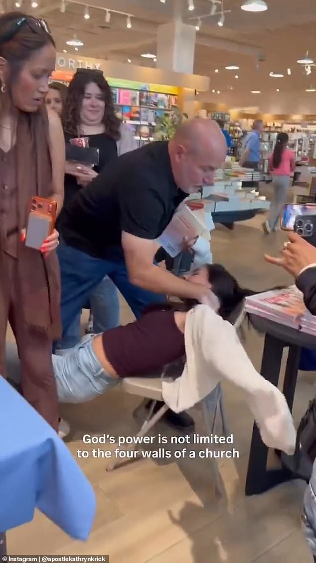 The woman’s knees buckled before she arched backward over a folding chair and was lowered to the bookstore floor