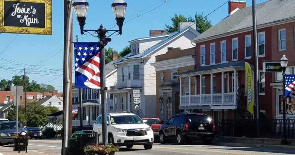 Historic Main Street in Boonsboro, Maryland, lined with brick storefronts, an American flag, and lamp posts.