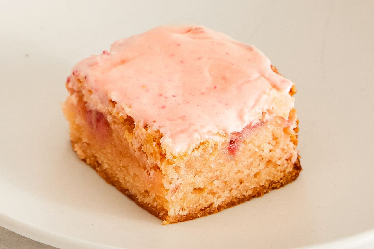 A strawberry brownie with pink frosting on a plate