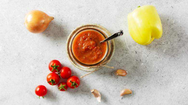 Sofrito sauce in glass jar from above surrounded by vegetables