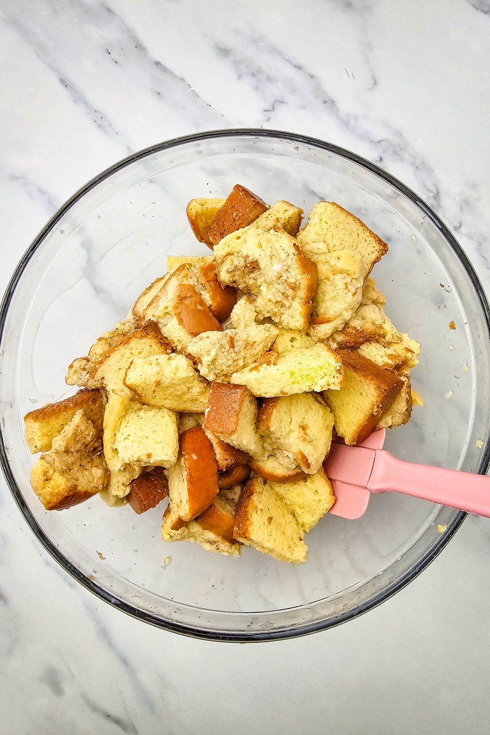 Brioche cubes soaked in cinnamon custard being folded with a spatula