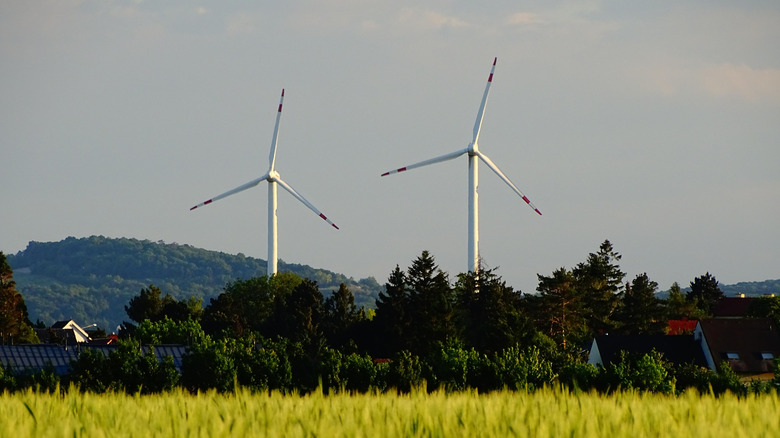 Two wind turbines near a grassy field