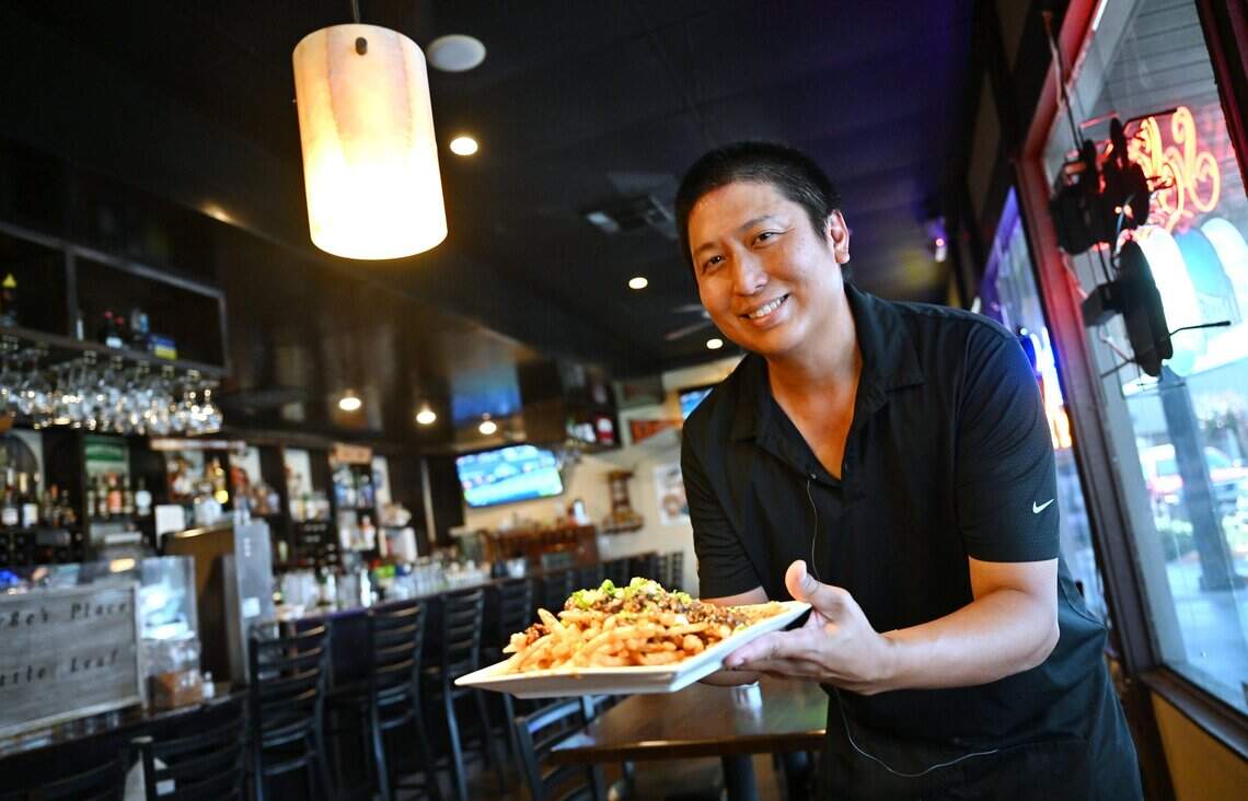 George Widjaja, owner of Little Leaf Bar & Restaurant, holds a plate of french fries at his fusion restaurant, bar and teahouse at Palm and Bullard avenues. Photographed Wednesday, July 15, 2026 in Fresno.