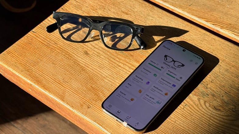 A pair of smart glasses connected to a phone on a wooden table