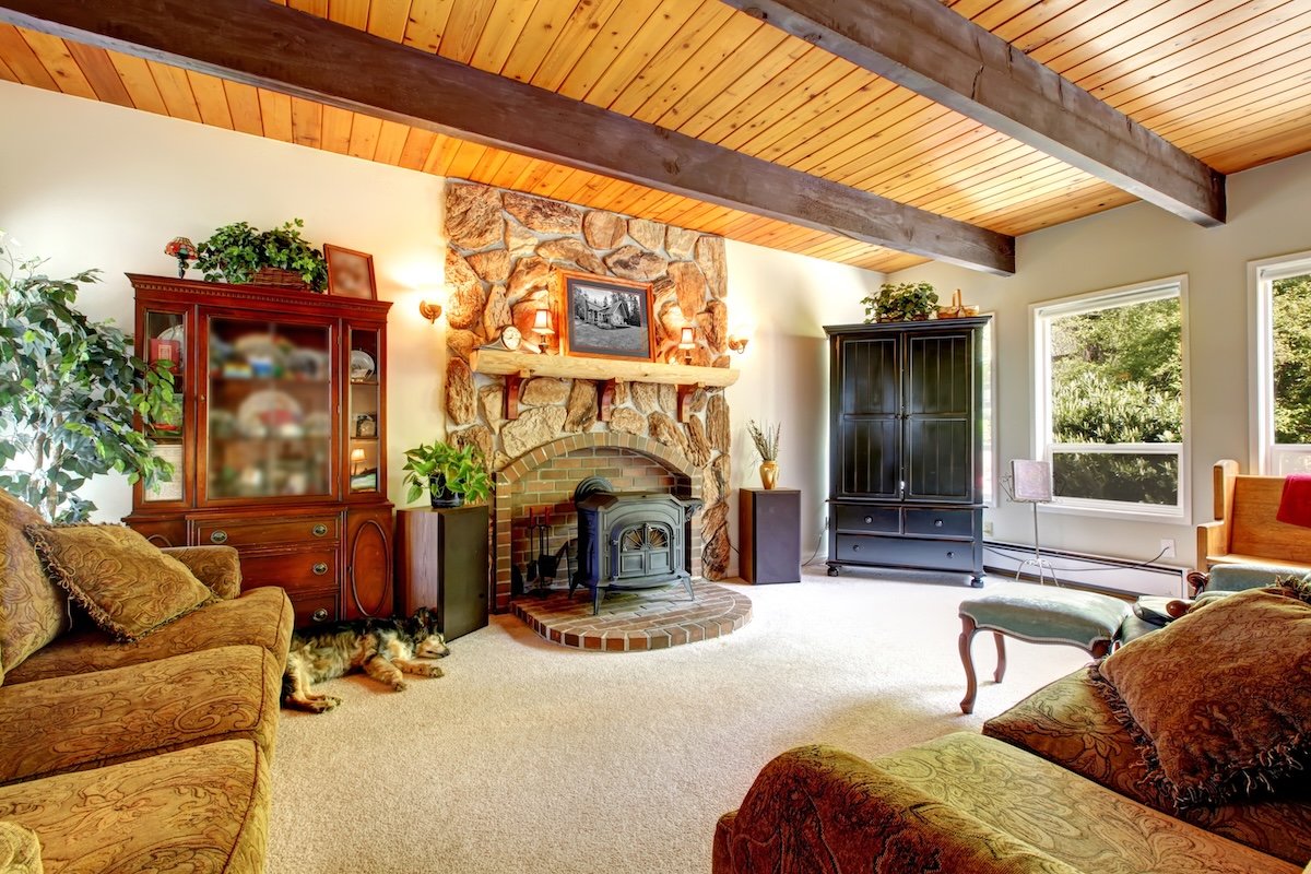 Living room of the farm house with wood ceiling and stone fireplace.