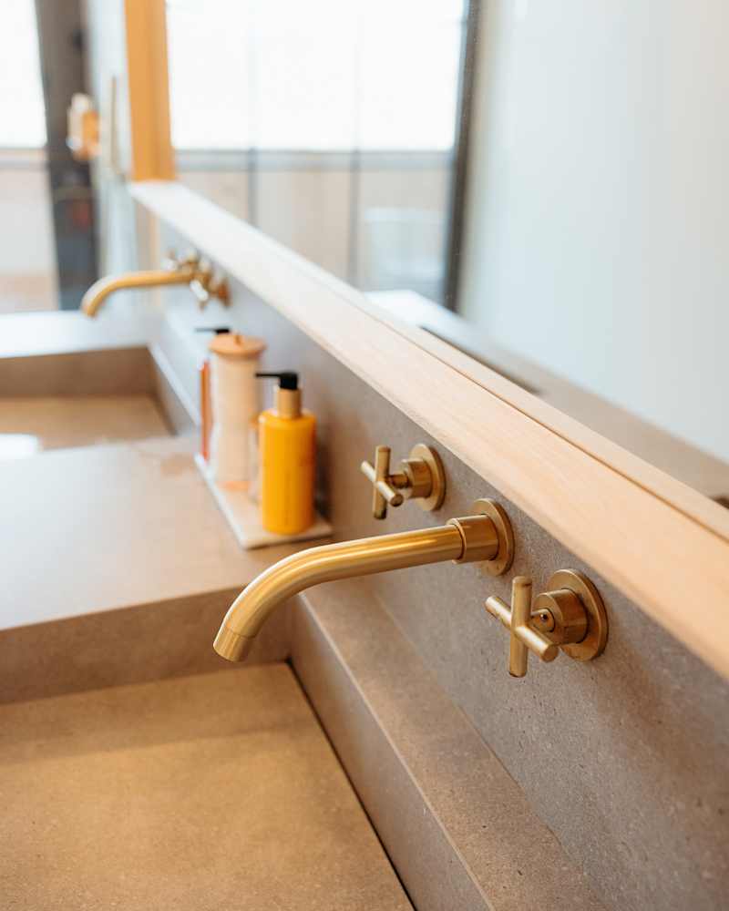 Brass bathroom sink faucet detail showing minimalist design in modern cabin bathroom