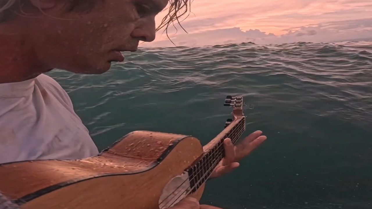Person plays music while surfing in Lombok, Indonesia