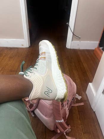 Stylish sneaker with textured sole and upper sits on a pink backpack on hardwood floor; casual and modern look ideal for shopping