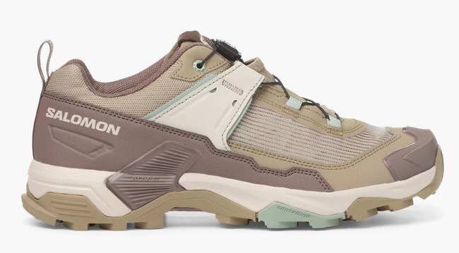 Trail running shoe with rugged, textured sole and supportive design. Suitable for outdoor activities, labeled