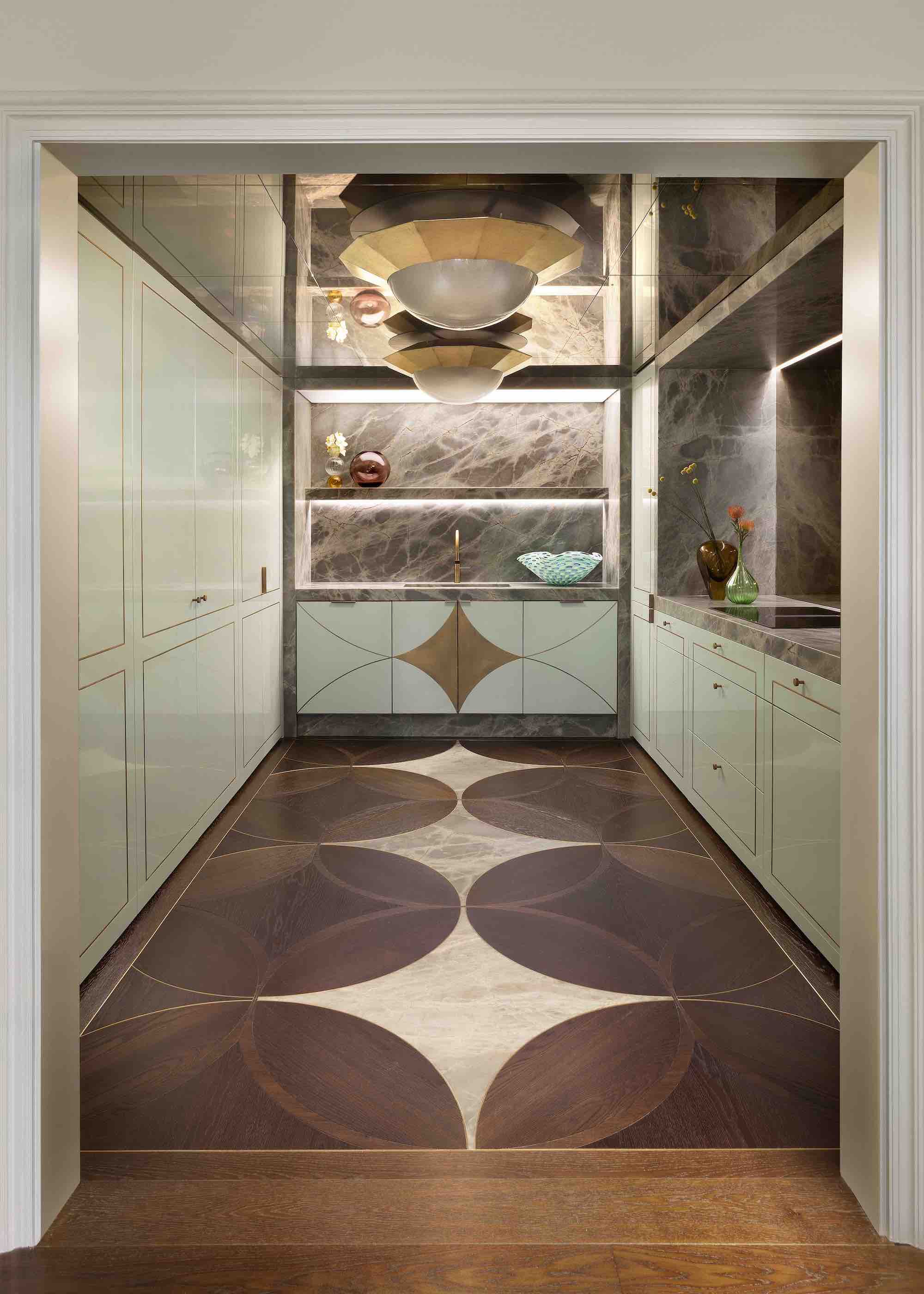 a small kitchen with mint cabinet doors with brass inlays, and a patterned wooden floor