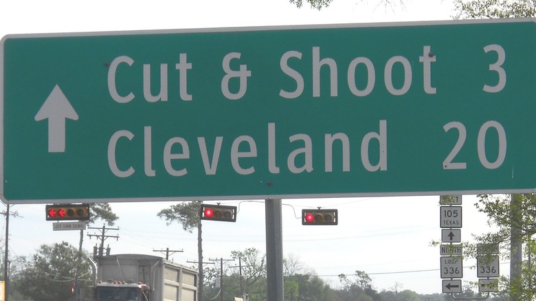 A road sign showing the distance to Cut & Shoot, Texas.