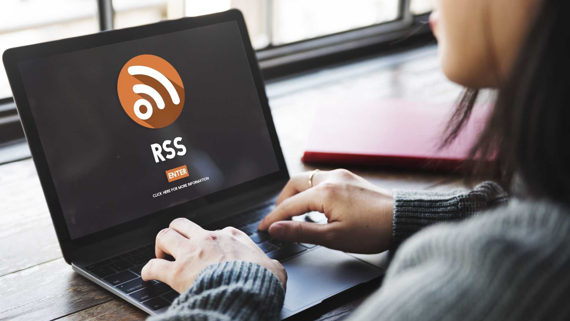 A woman sits in front of a laptop showing the RSS logo.