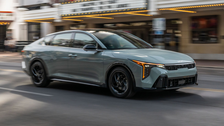 pale teal 2026 Kia K4 driving past the Paramount Theatre in Austin, Texas