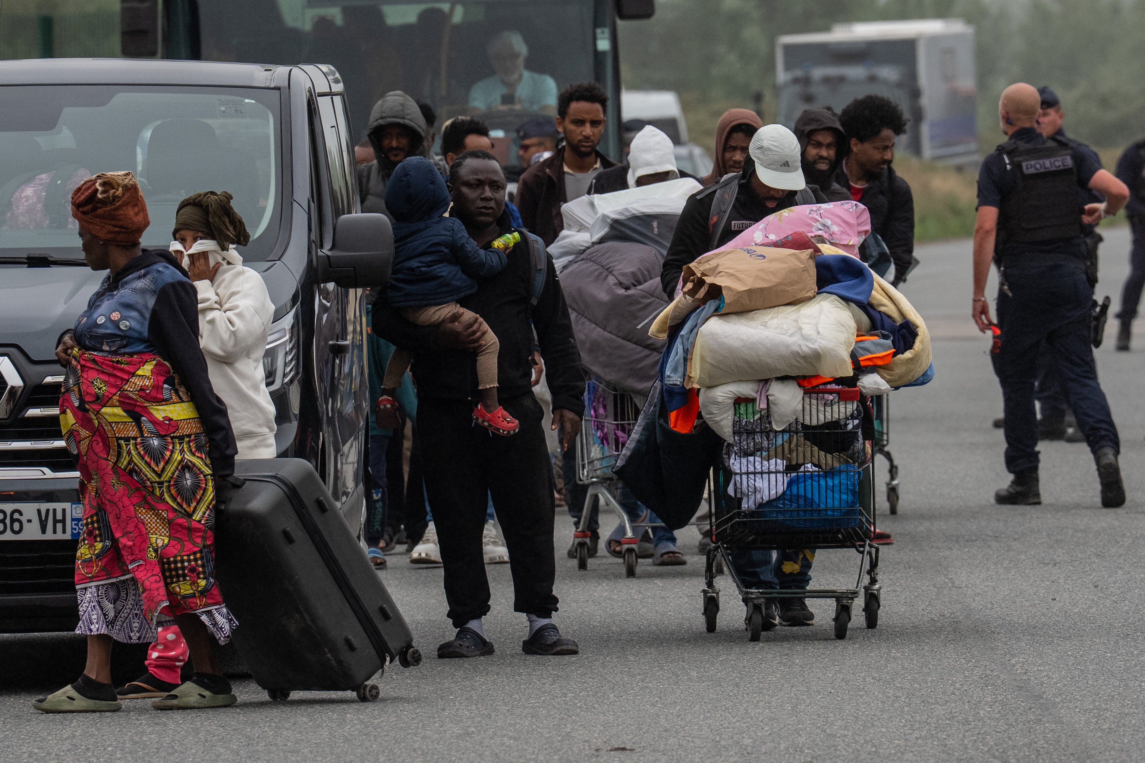 Migrants leave an area of their camp that was cleared by French authorities on 2 July 2026 in Loon-Plage, France. (Getty)