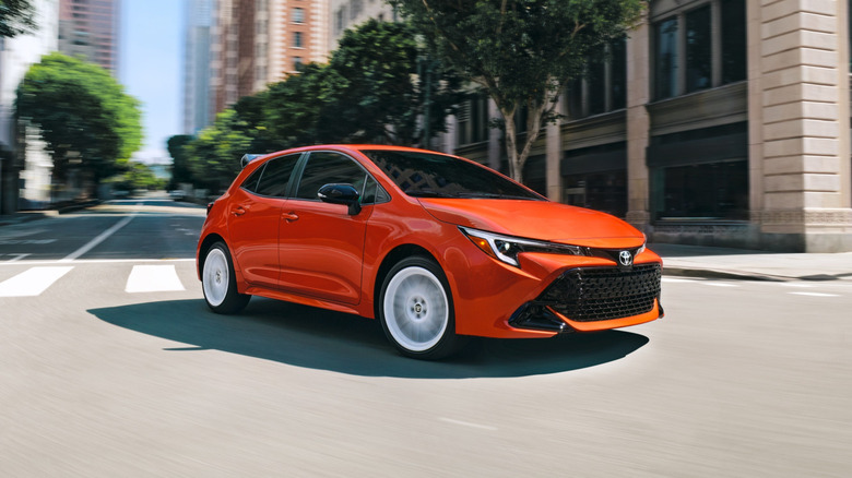 orange 2026 Toyota Corolla FX turning a corner in an urban downtown