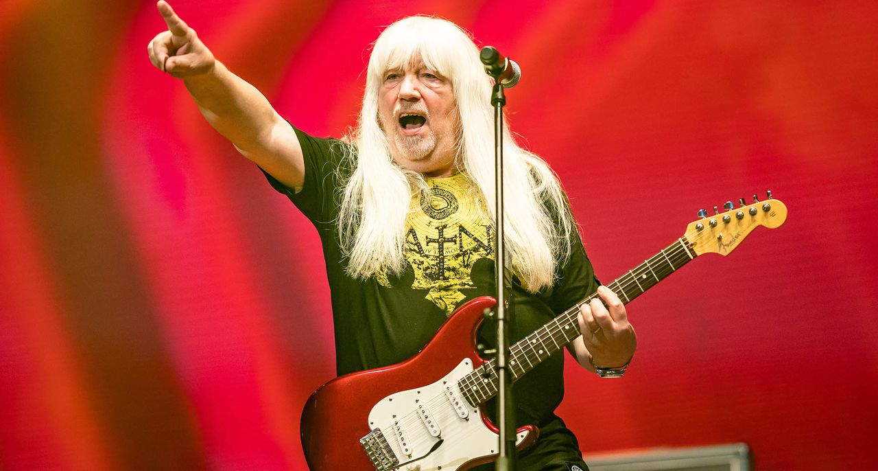 Andy Scott of the Sweet points to the crowd has he plays a red Strat