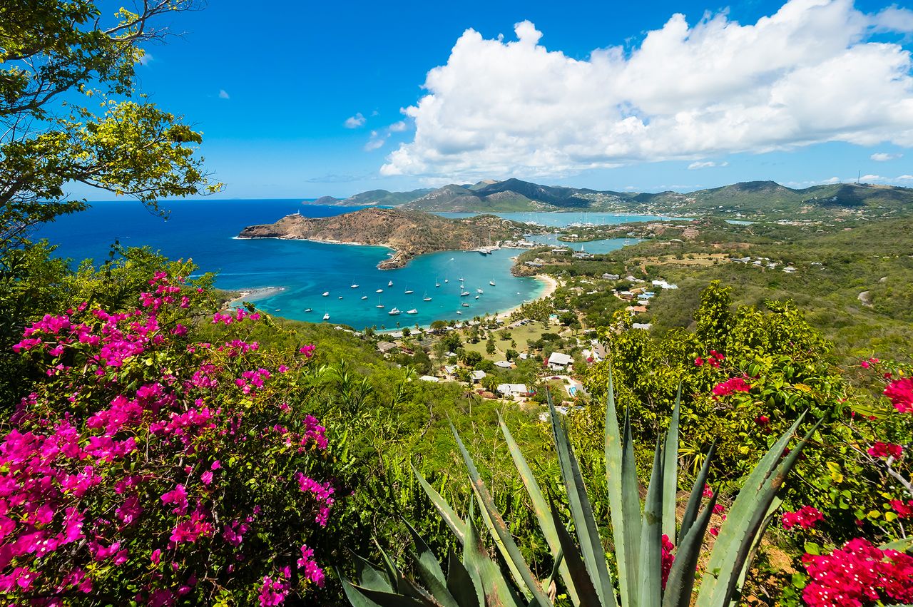 Scenic view of a tropical bay surrounded by lush vegetation mountains in the background and clear blue water