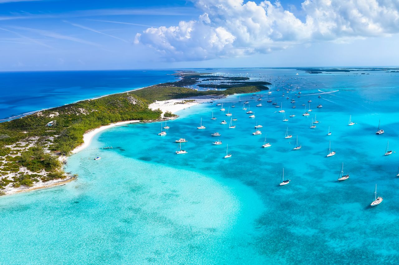 An aerial view of numerous sailboats anchored near an island in the Caribbean