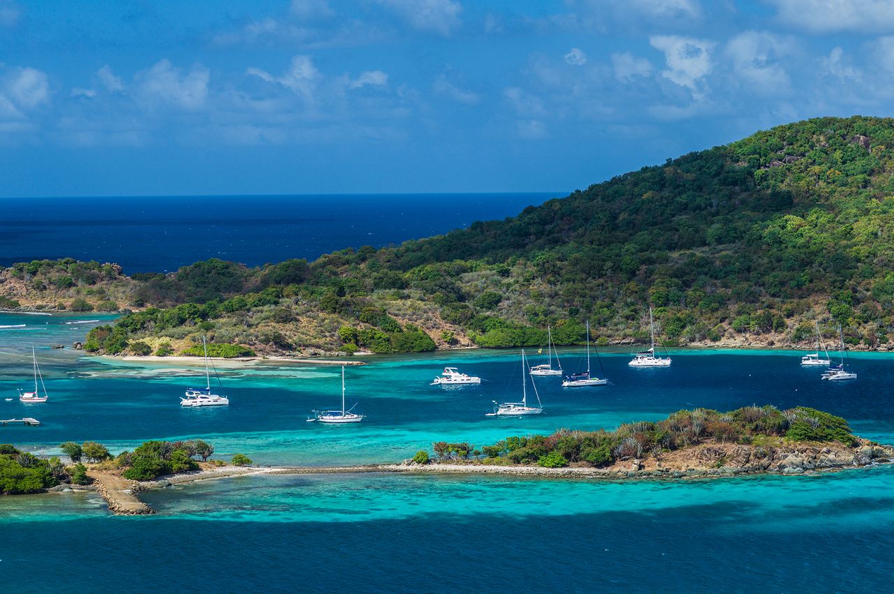 Coastal bay surrounded by hills sailing boats anchored in clear water