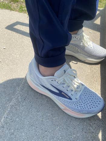 Person wearing athletic shoes with mesh design and comfortable cushioning, standing on concrete steps