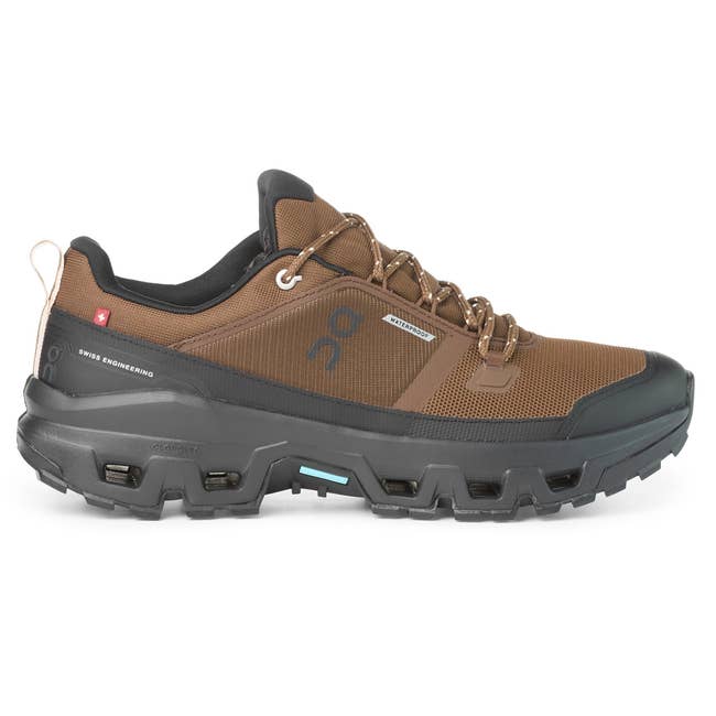 Brown hiking shoe with a rugged black sole, featuring branding on the side and detailed lacing. Suitable for outdoor activities
