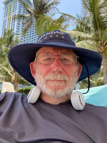 A person in sunhat and glasses with the fan around neck