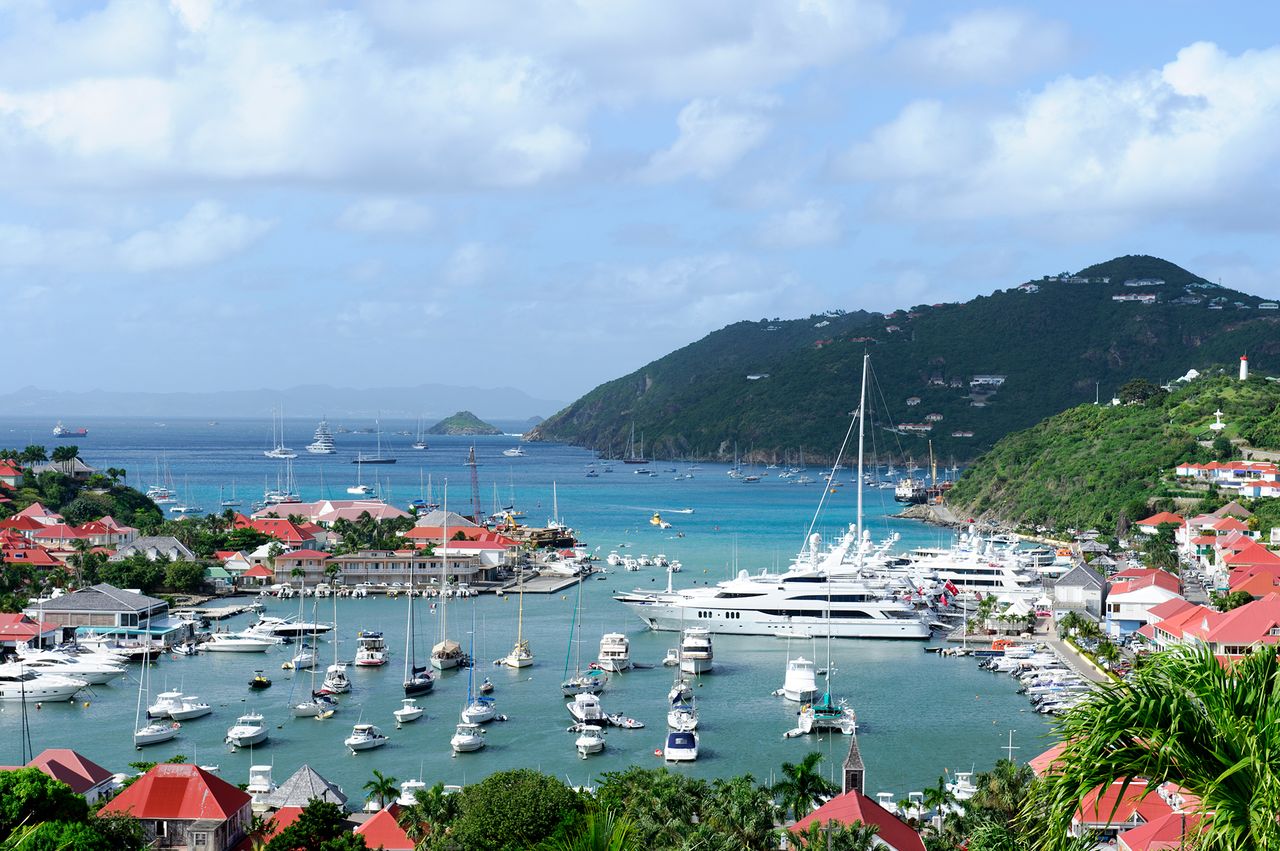 A harbor with yachts and sailboats surrounded by buildings and hills