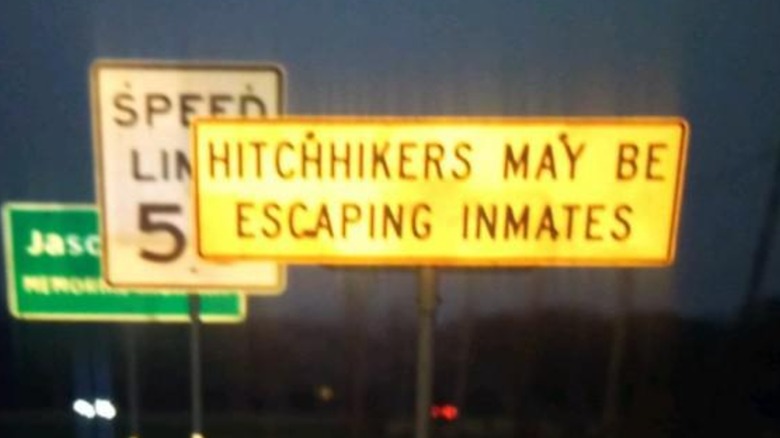 A "Hitchhikers May be Escaping Inmates" sign taken at night along a road in Texas.