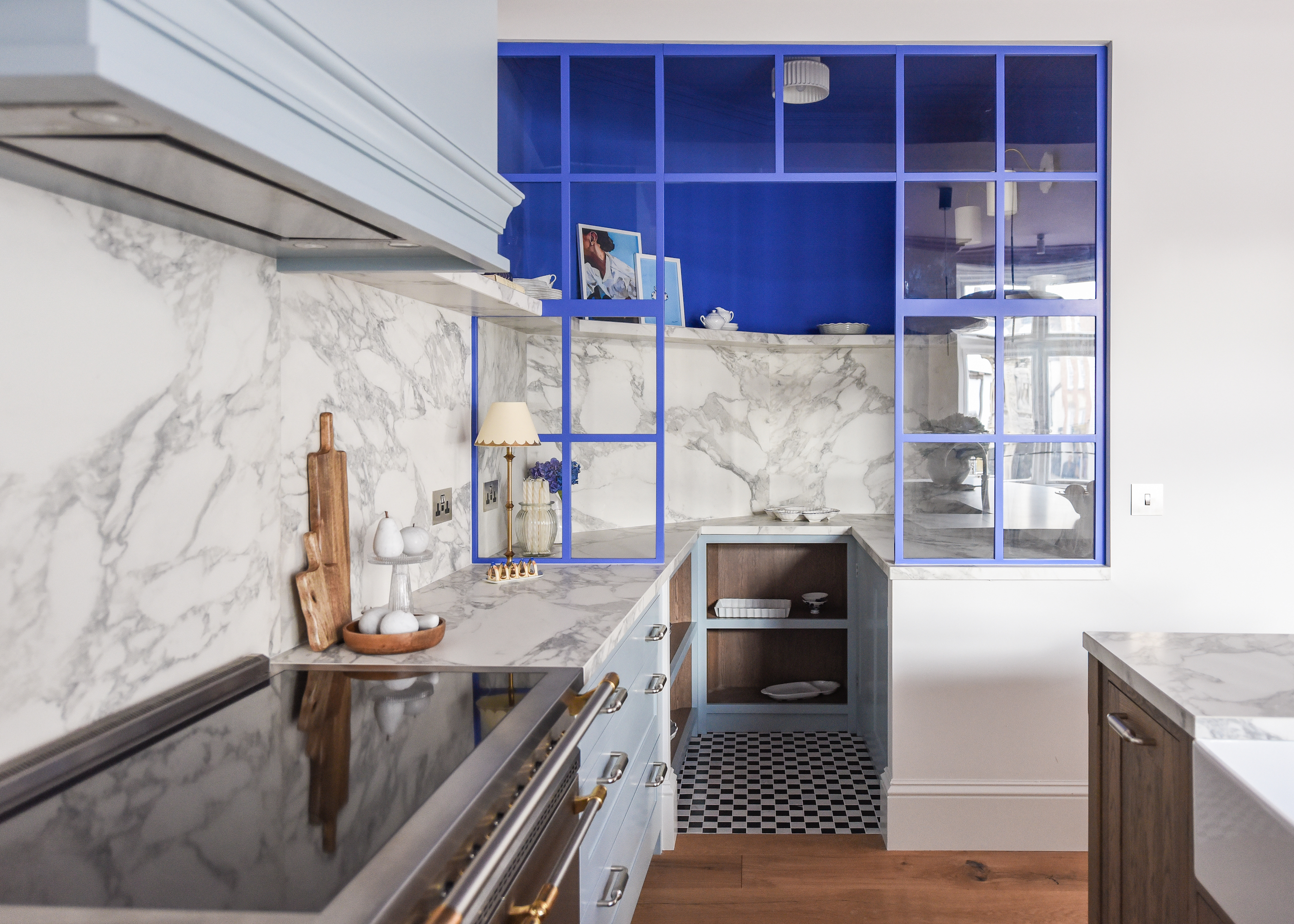 two tone light blue kitchen with a separate pantry divided by a glass and metal screen, painted in an electric blue.